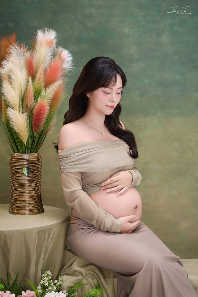 Mom ngồi ôm bụng bên bình cỏ lau